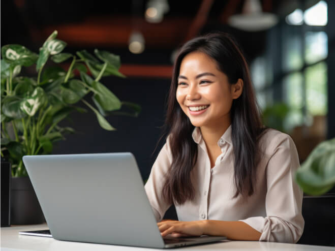 A young Indigenous woman smiling at a laptop