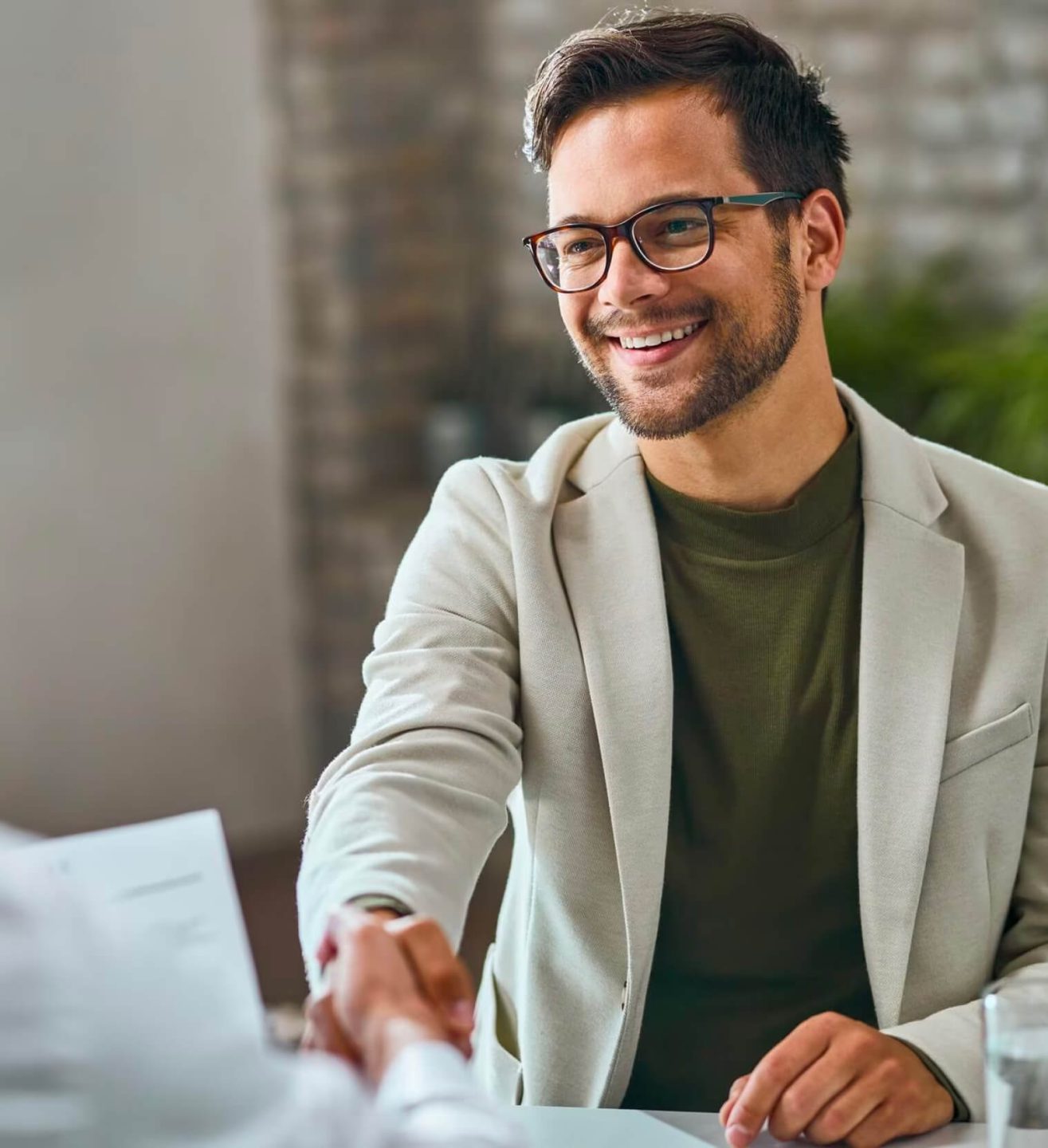 Young man in glasses and a blazer shaking hands with someone