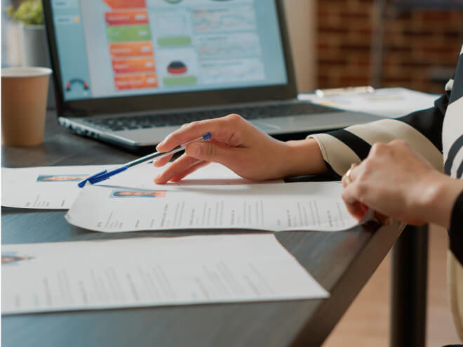 A photo of two female hands looking at document holding a pen