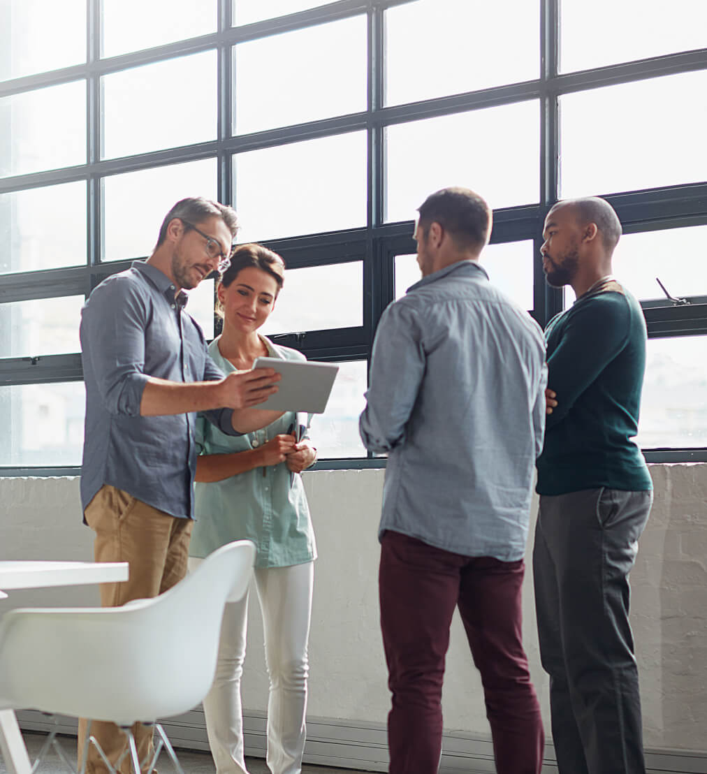 A diverse group of young adults facing each other and looking at a tablet
